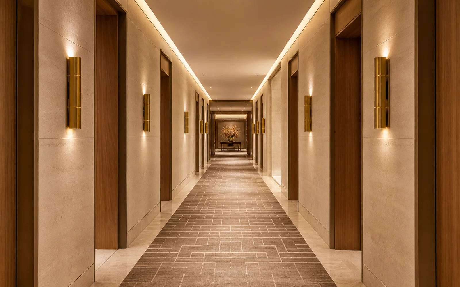 Contemporary luxury hotel corridor with limestone walls, walnut doors, brass sconces, and a centered one-point perspective.