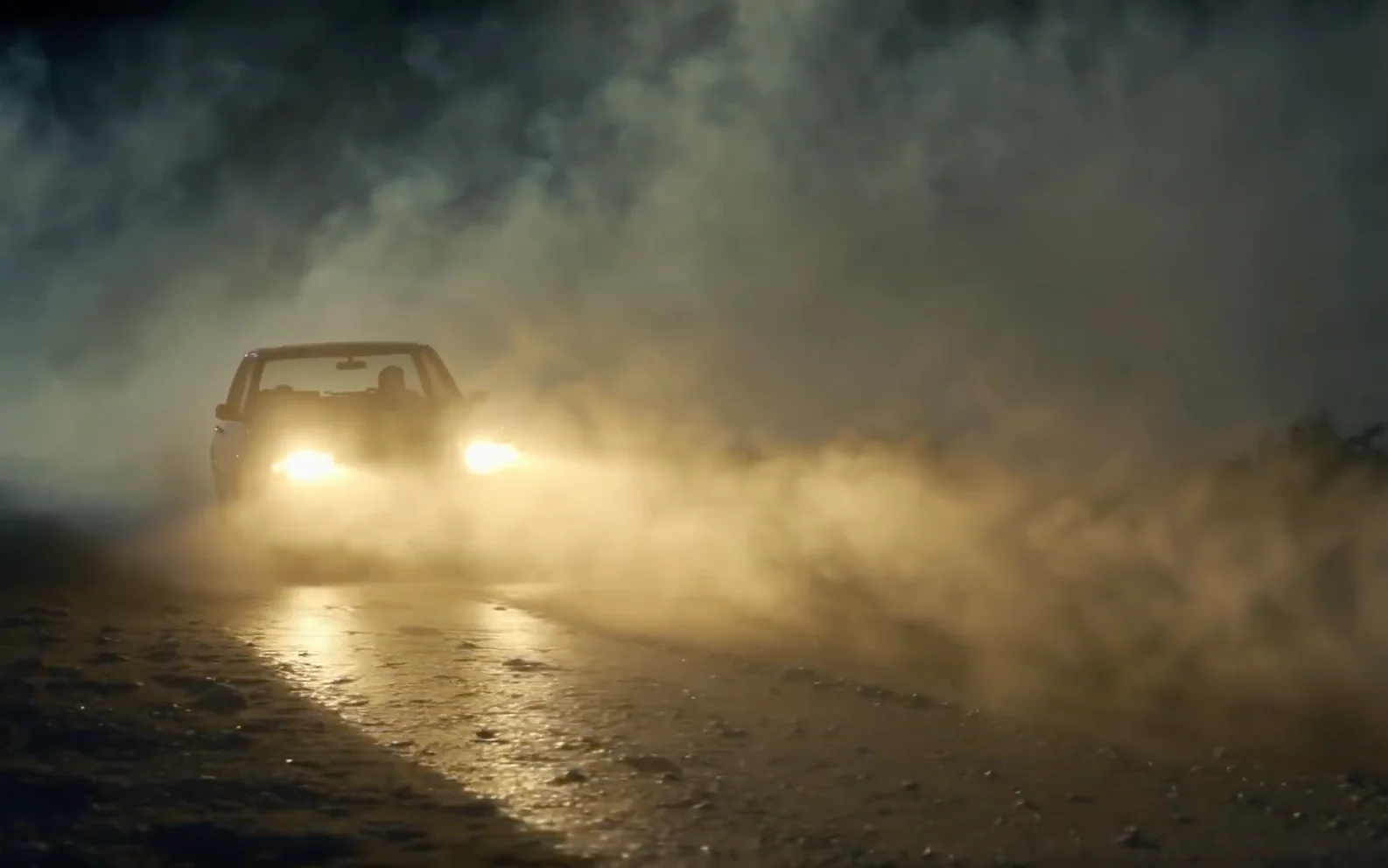 Compact crossover headlights cutting through dense fog on a wet rural road at night.