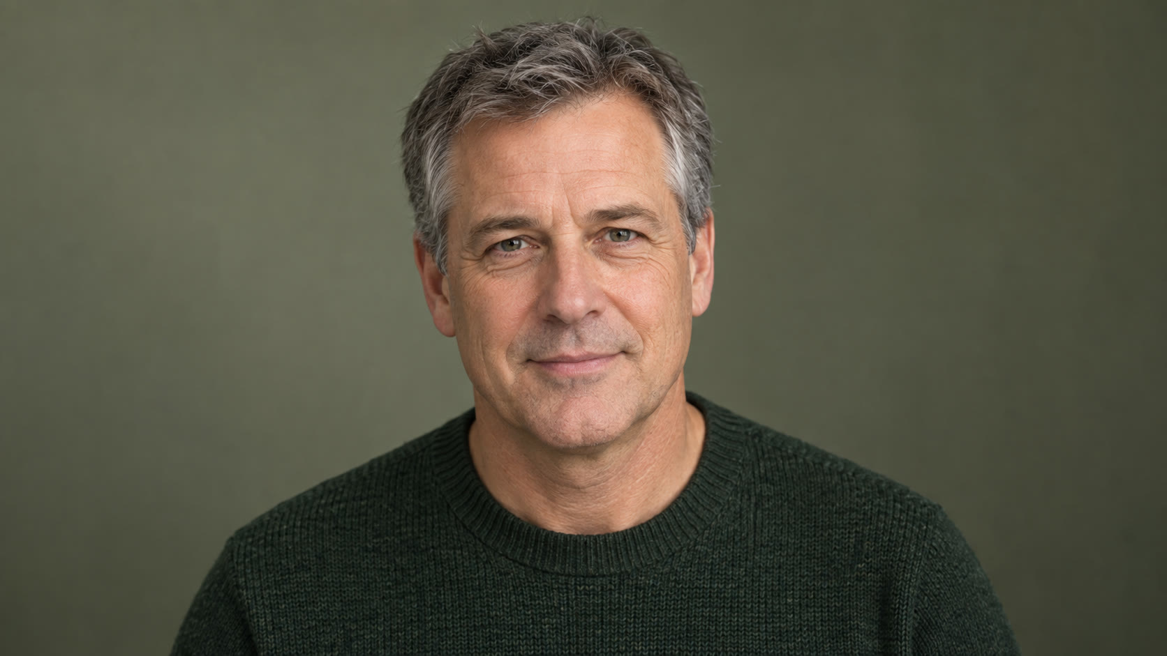 Man with gray hair in a dark green sweater